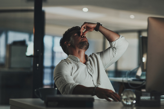 Hombre cansado en el trabajo, frente a su computadora